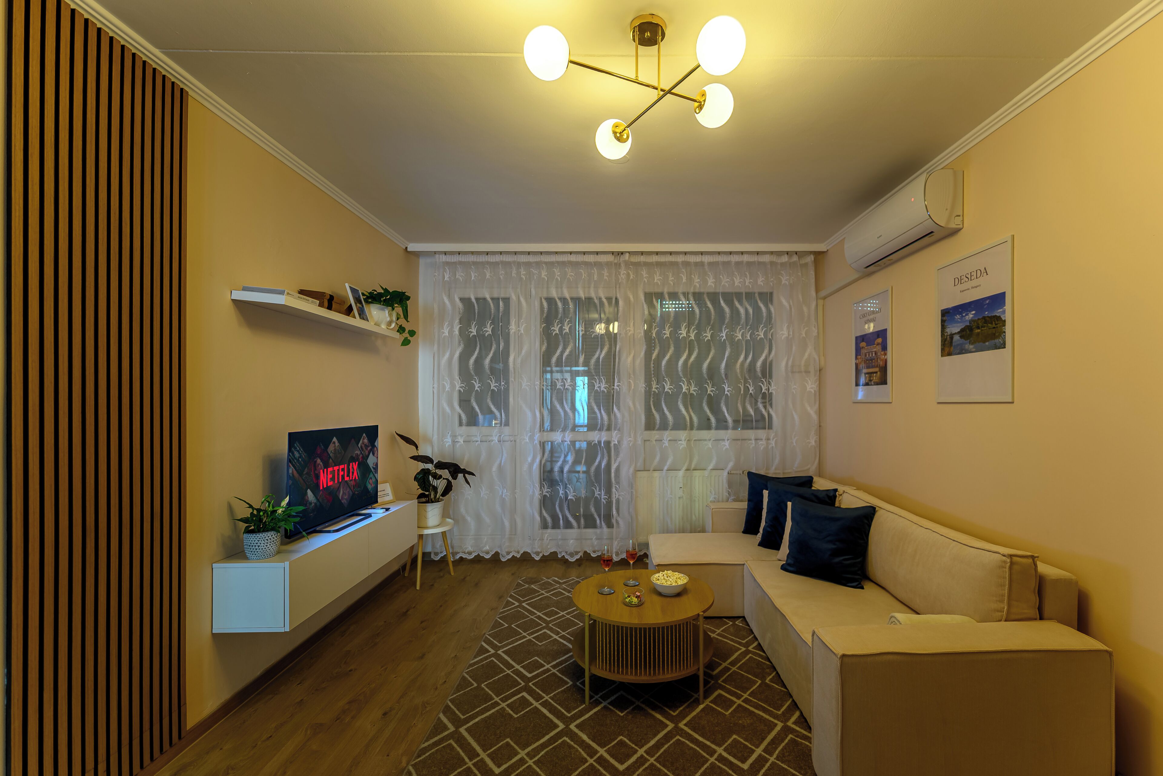 A living room with a sofa, a coffee table, a TV, and a window with curtains.