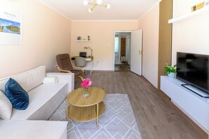 Una sala de estar moderna con un sofá, una mesa redonda de centro, un televisor y un escritorio con una silla.