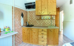 Una cocina compacta con armarios de madera, horno integrado y una pequeña encimera.