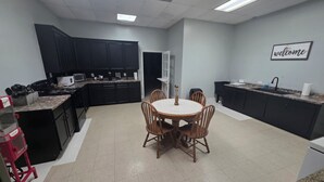 Een moderne keuken met donkere kastjes, een centraal eiland en een eethoek met een ronde tafel en stoelen.