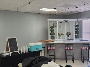 A bar area with a counter, stools, and decorative plants.