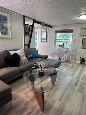A living room with a glass coffee table, grey sofa, and a dining area with white chairs. - White River Cabin - Private
Dock & Wildlife (Gosport)