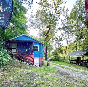 A blue cabin with a red staircase, surrounded by trees and a gravel path. - White River Cabin - Private
Dock & Wildlife (Gosport)