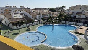 Une piscine de forme circulaire, entourée de bâtiments de style architectural méditerranéen.