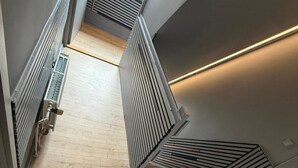 A modern staircase with a wooden floor, metal railings, and a skylight.