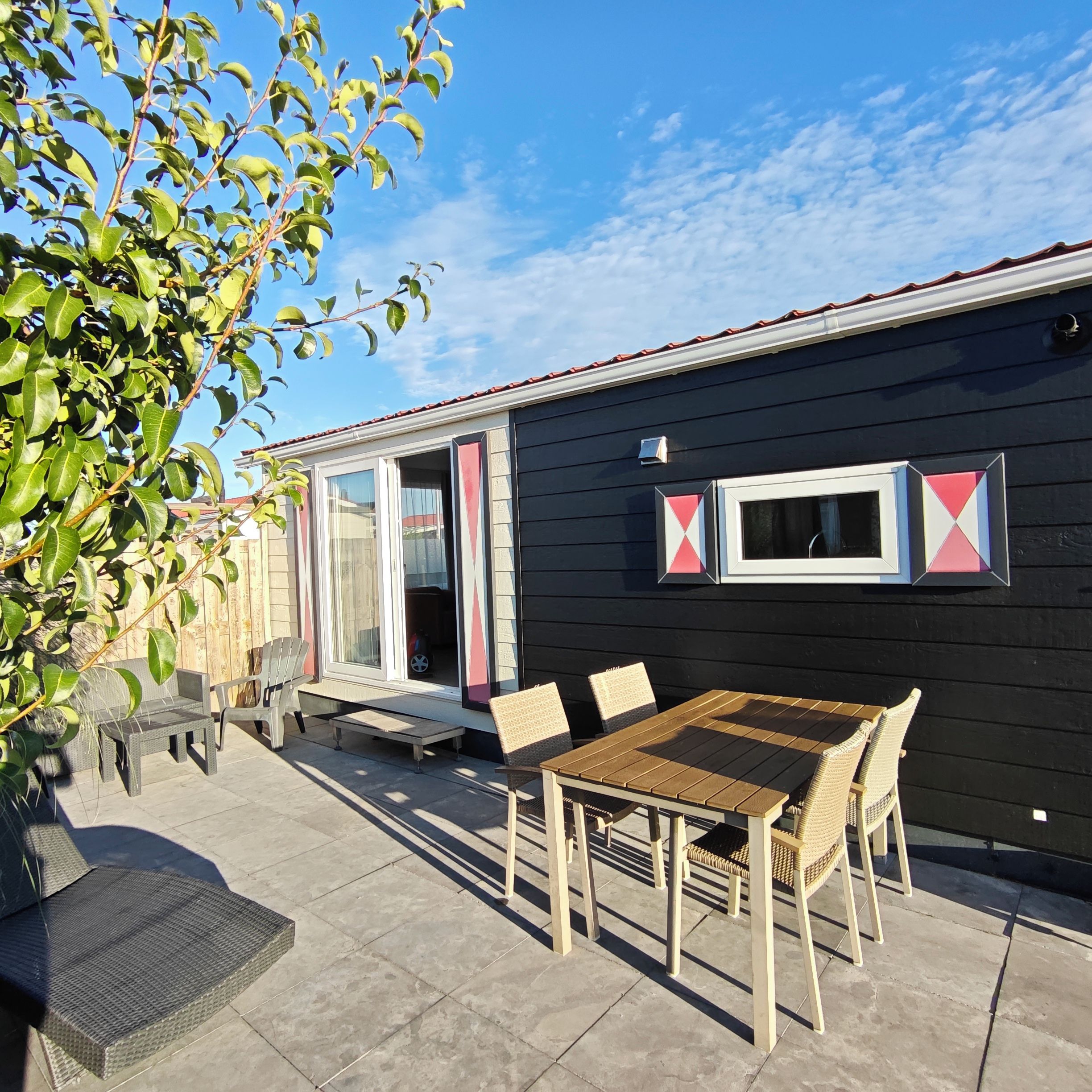 A patio area with a table and chairs, a small bench, and a door leading to a covered space.