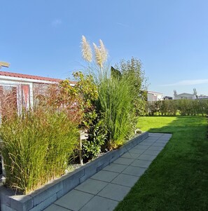 A garden with various plants and a pathway. - Modern 4-person chalet in Zeeland—near the beach, Veere, Middelburg, and Domburg (Serooskerke)
