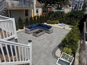 Eine Dachterrasse mit einer Eckcouch, einem Glastisch und einem kleinen Tisch mit Stühlen.