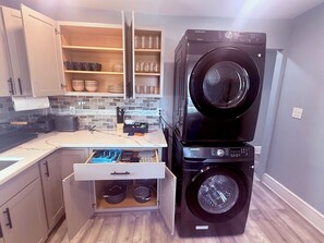 Eine kleine Küche mit integriertem Waschtrockner, einer Arbeitsplatte mit Toaster und einer Schublade für Töpfe.