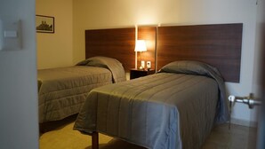 A hotel room with two beds, a nightstand with a lamp, and a framed picture on the wall. - Hotelito Casa Anzures (Puebla)