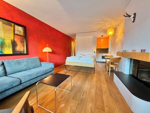 Ein gemütlicher Raum mit einem Bett, einer Couch, einem kleinen Tisch und einem Kamin.