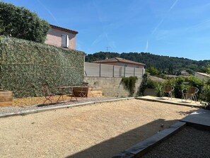 A patio area with a gravel surface, a wooden deck, and two metal chairs. - Magnificent Villa With Swimming Pool in Marseille (Marseille)