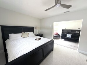 A bedroom with a bed, a nightstand, a lamp, a ceiling fan, a chair, and a bookshelf.