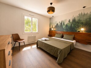 A bedroom with a bed, a chair, a desk, a radiator, and a window with a view of trees. - FAMILY VILLA 190 m² (190 sq.m.) - UP TO 14 PEOPLE - GARDEN 2 500 m² - BEACHES 5 min away (Vendays-Montalivet)