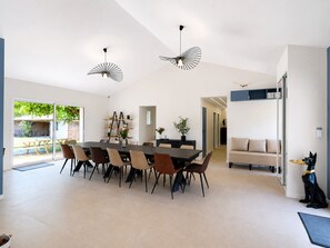 A modern dining area with a large table, chairs, and unique ceiling fans. - FAMILY VILLA 190 m² (190 sq.m.) - UP TO 14 PEOPLE - GARDEN 2 500 m² - BEACHES 5 min away (Vendays-Montalivet)