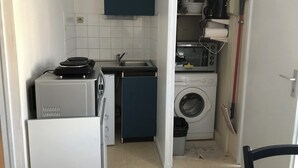 Cocina compacta con lavadora, microondas y un lavamanos pequeño.