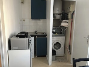A compact kitchen with a washing machine, a microwave, and a small sink.