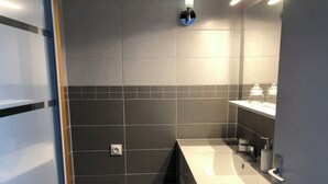 Un baño moderno con baldosas oscuras, un lavamanos y un espejo.