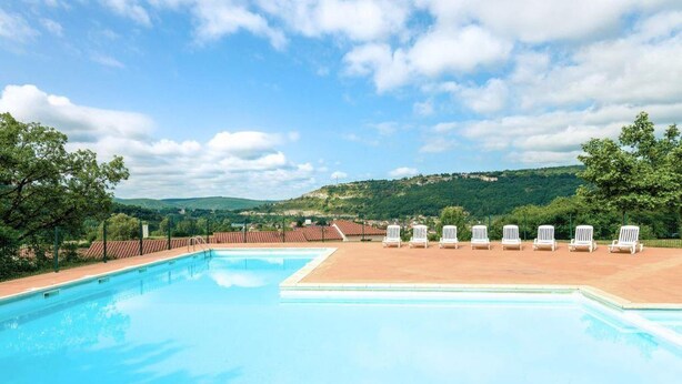 A swimming pool with lounge chairs, surrounded by a fence, and a view of hills in the background. - Lovely Duplex Near Historic Carayac (Carayac)