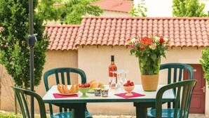 A table set outdoors with a view of a red-tiled roof building, a potted plant, and various food items. - Lovely Duplex Near Historic Carayac (Carayac)