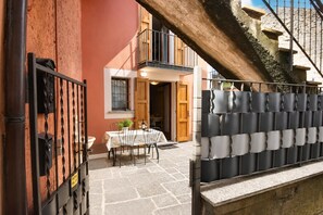 Ein Innenhof mit Tisch, Stühlen, einem Balkon und einer Treppe.
