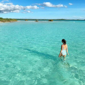 A woman in a swimsuit standing in clear turquoise water. - HEADLINE CAMPER 1 (Bacalar)