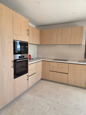 Eine moderne Küche mit Holzausstattung, einer eingebauten Mikrowelle und einem Edelstahlbackofen.