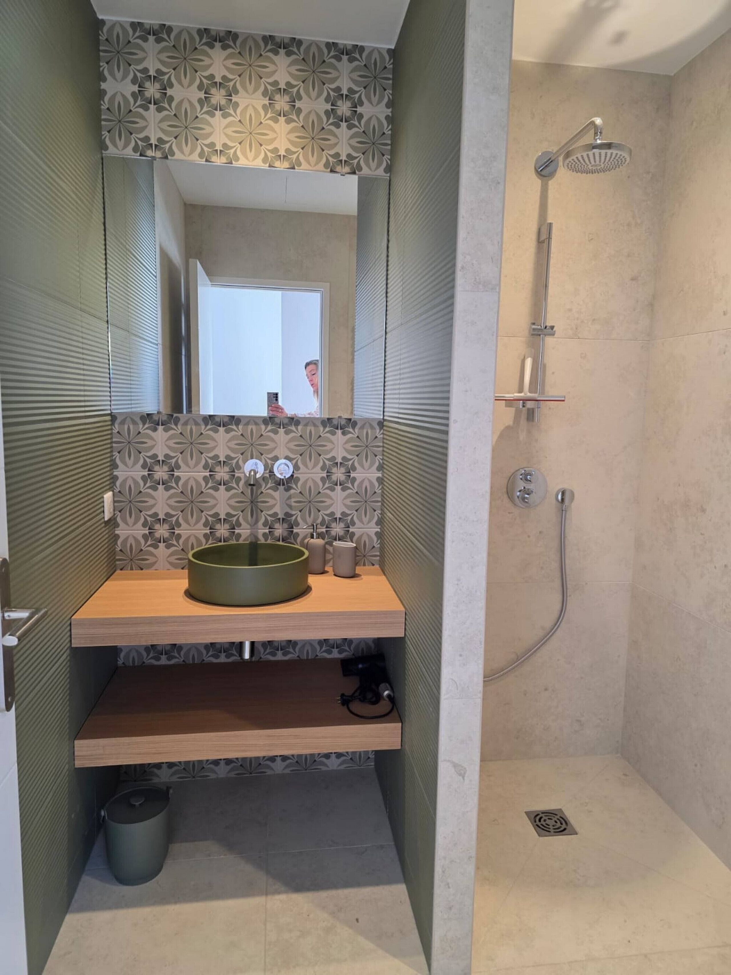 Une salle de bain au design moderne, dotée d’un grand miroir, d’un lavabo rond et d’une douche.