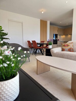 Ein modernes Wohnzimmer mit einer Couch, einem Couchtisch und einem Essbereich mit Stühlen und einem Tisch.