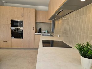 Eine moderne Küche mit Holzausstattung, einem Backofen, einer Spüle und einer Arbeitsplatte.