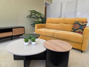 Ein Wohnzimmer mit einer Couch, einem Couchtisch, einem Beistelltisch und einer Topfpflanze.