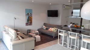 A modern living room with a sofa, a coffee table, a TV, and a bar area with stools. - Nice T3 in Juan les pins (Antibes)