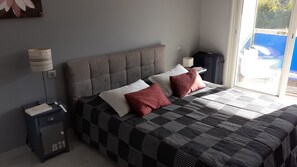 A bedroom with a bed, pillows, a nightstand, a lamp, and a suitcase. - Nice T3 in Juan les pins (Antibes)