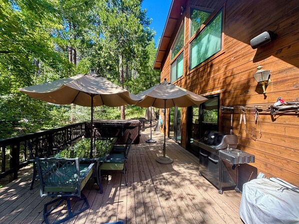 Una terraza de madera con mobiliario exterior, sombrillas y una zona de barbacoa.