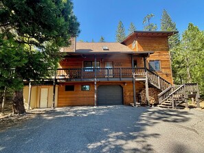 A two-story log cabin with a balcony, a garage, and a staircase leading to the upper level.