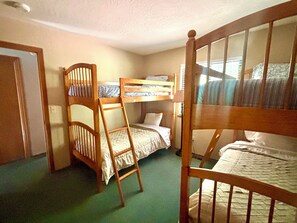 Une chambre avec un lit superposé, une échelle, une porte et une fenêtre.