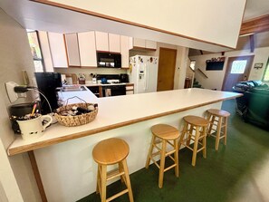 Une cuisine dotée d’un îlot central, de tabourets de bar et d’une moquette verte.