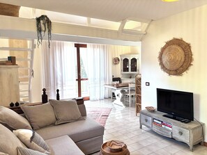 A living room with a sofa, television, and a dining area with a table and chairs. - Grace House - Spacious Villa in a Prime Location Between Castelsardo and Alghero (Arboriamar)