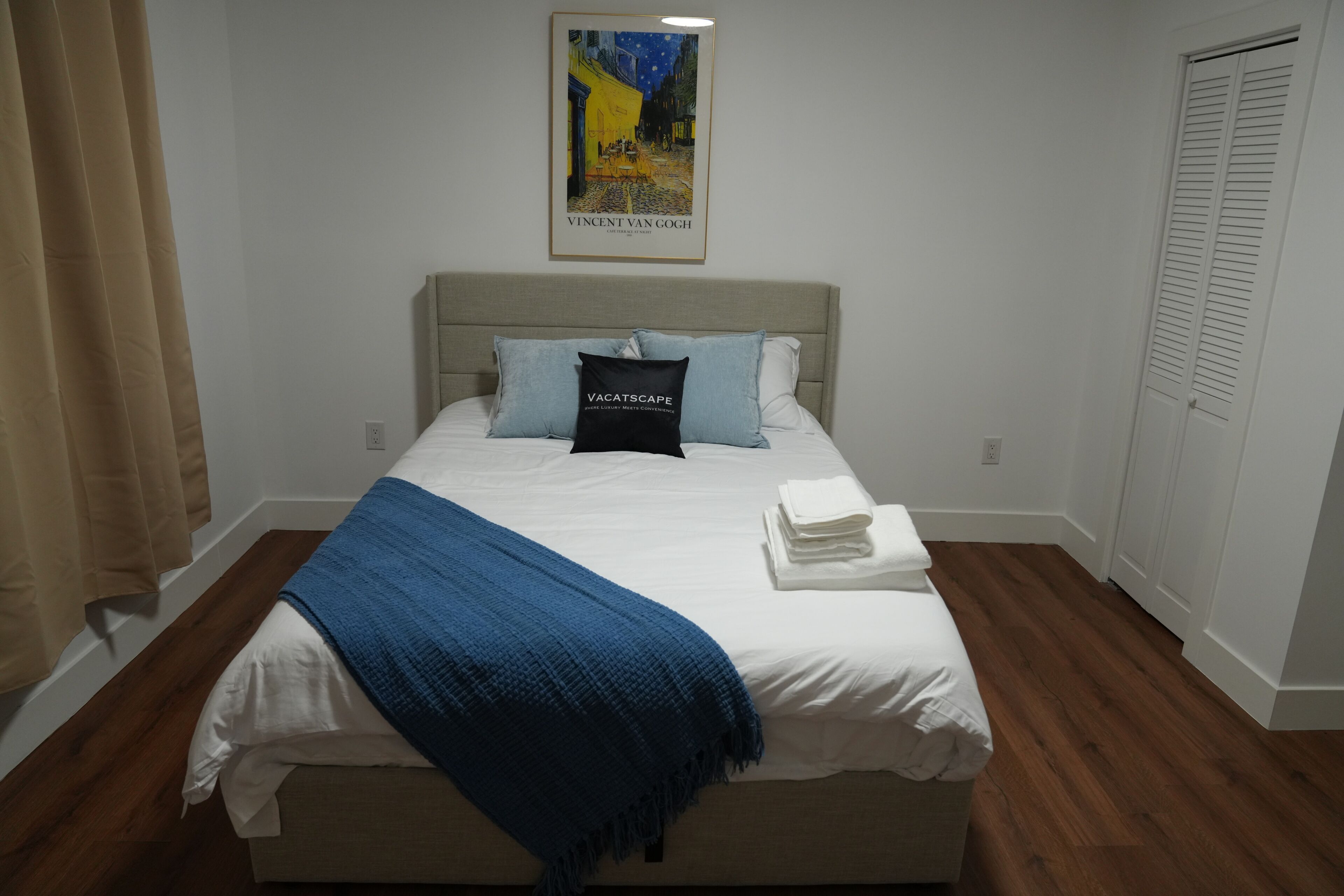 A neatly made bed with a blue blanket, a pillow, and a folded towel.