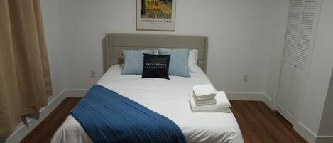 A neatly made bed with a blue blanket, a pillow, and a folded towel.