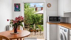 Ett kompakt kök med tvättmaskin, mikrovågsugn och en matplats med bord och stolar.