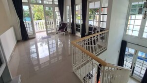 A spacious room with a balcony, large windows, and a staircase. - Cozzy Villa Rans Cimacan (cianjur)