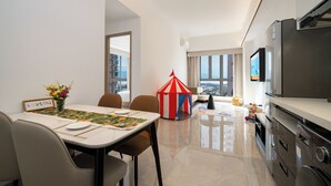 A modern living room with a dining area, a kitchen, and a large window offering a city view. - YEENFON HOTEL (Shenzhen)