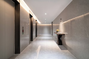A modern hallway with elevators, a reception desk, and a wall-mounted sign. - YEENFON HOTEL (Shenzhen)