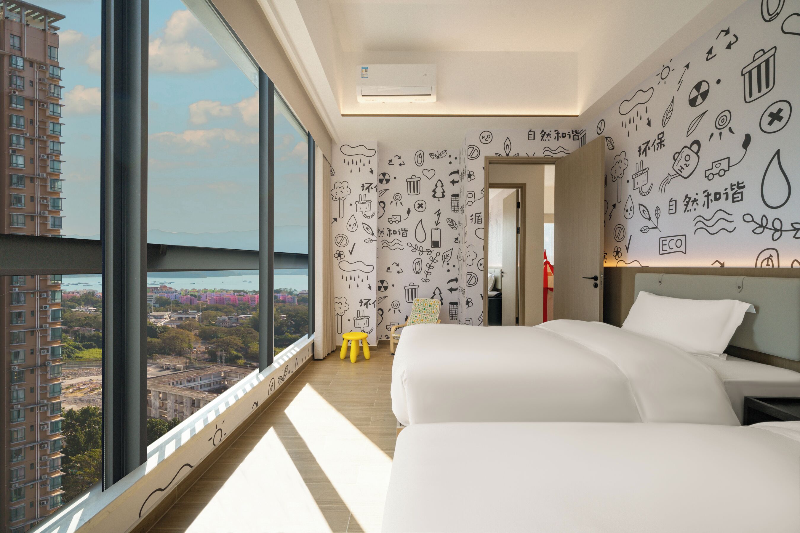 A modern hotel room with large windows, a bed, a small stool, and walls decorated with environmental icons.