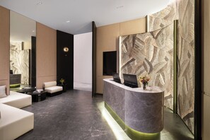A modern reception area with a curved marble counter, seating, and a decorative wall pattern. - YEENFON HOTEL (Shenzhen)