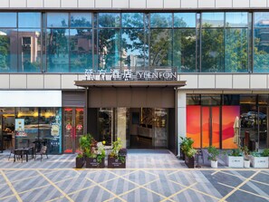 A modern hotel entrance with a glass facade, outdoor seating area, and potted plants. - YEENFON HOTEL (Shenzhen)