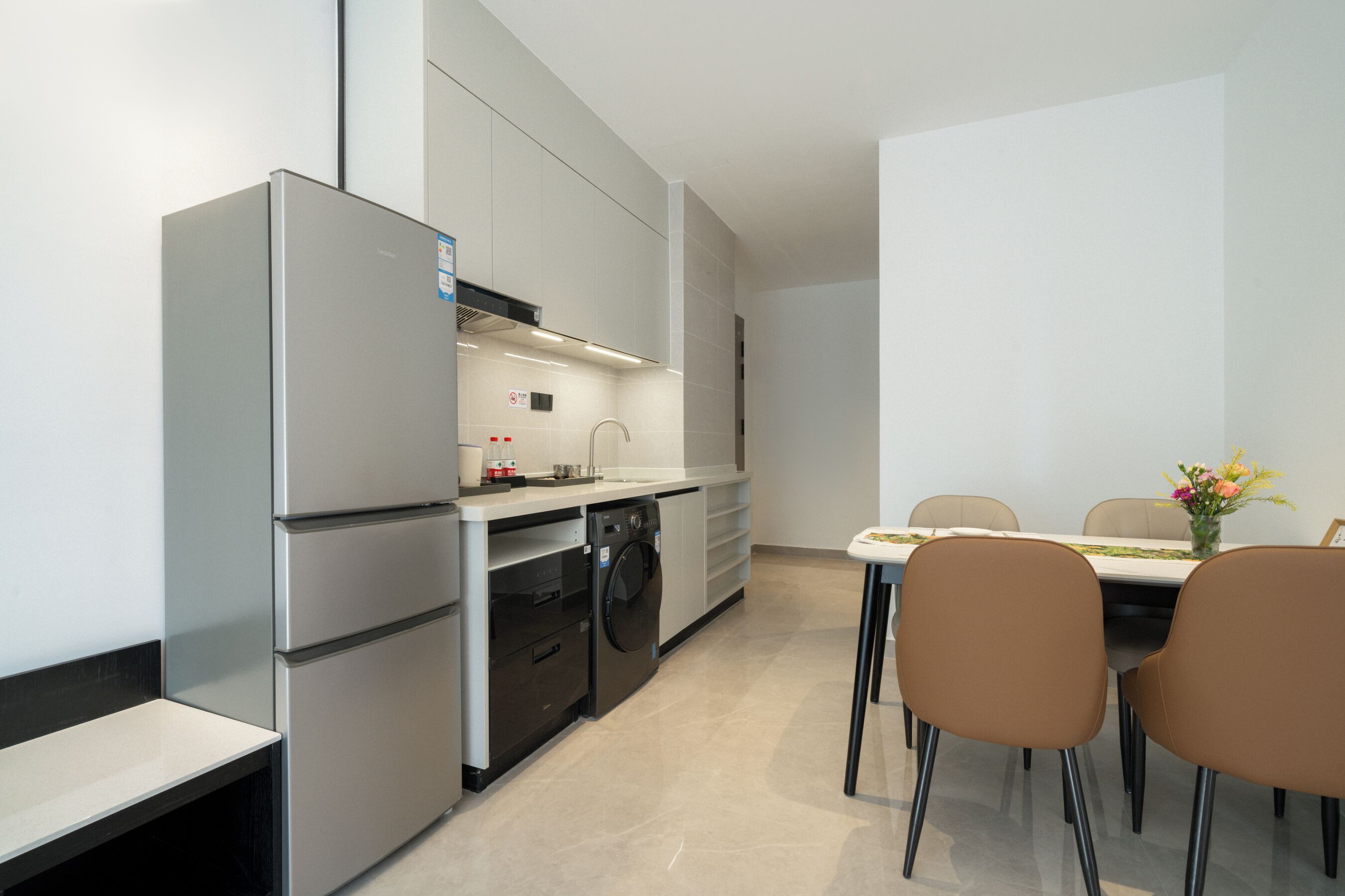 A modern kitchen with a built-in washing machine, a dining table with chairs, and a small dining area.