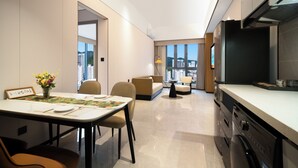 A modern hotel room with a dining area, a sofa, a TV, and a kitchen area. - YEENFON HOTEL (Shenzhen)