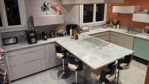 A modern kitchen with a central island, bar stools, a coffee station, and decorative items. - 3-bedroom single-family home, 3 km from the beaches and close to everything: restaurants, movie theater, park, and sports facilities (La Garde)
